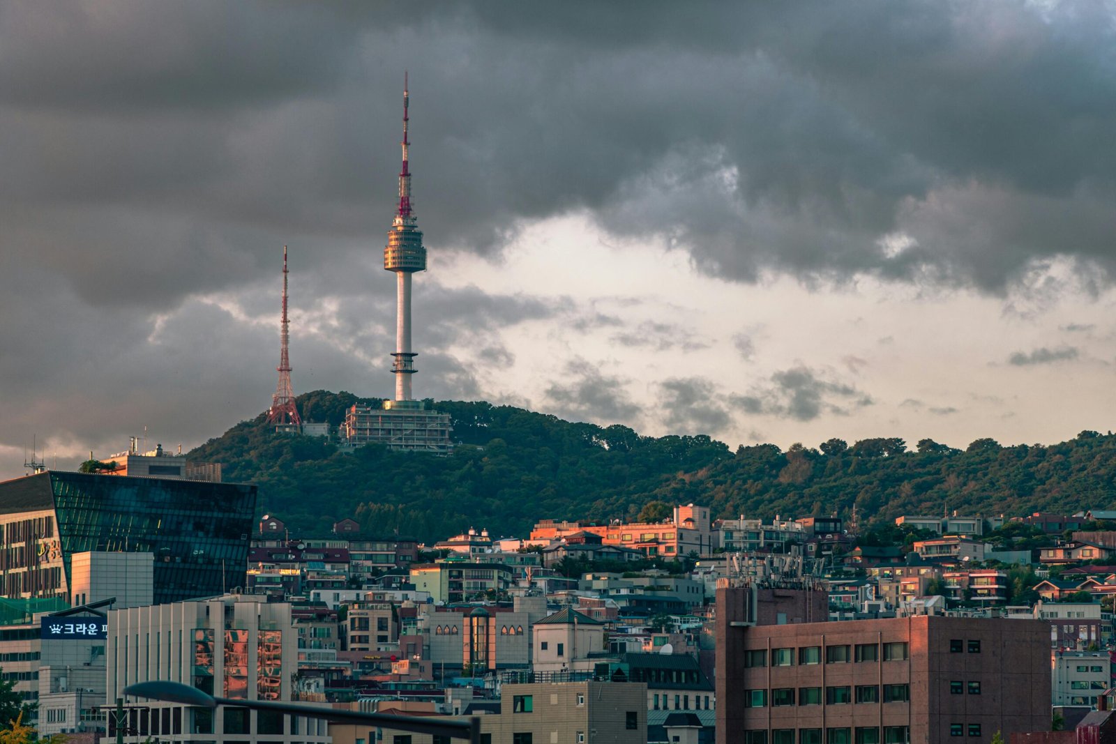 A stunning view of Seoul, South Korea's Namsan Seoul Tower surrounded by city buildings and dramatic clouds.